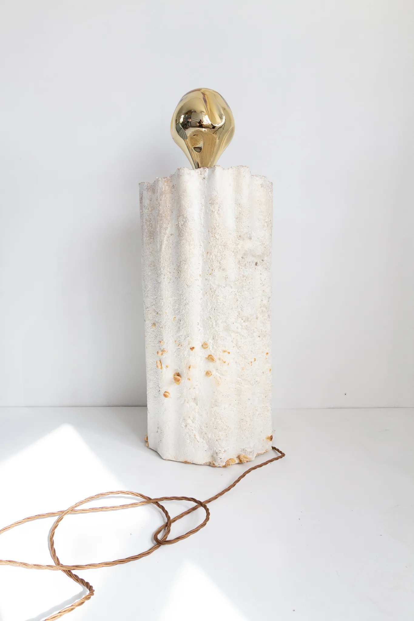 A freestanding mycelium lamp with a sculptural white, fibrous body